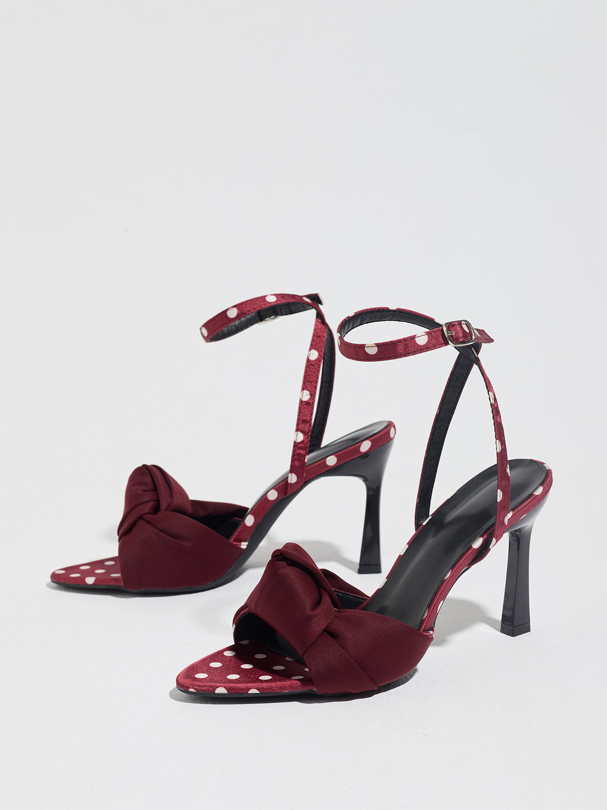 Mescini burgundy knot front polka dot heeled sandals, pair standing on a pale grey surface, US women's sizes