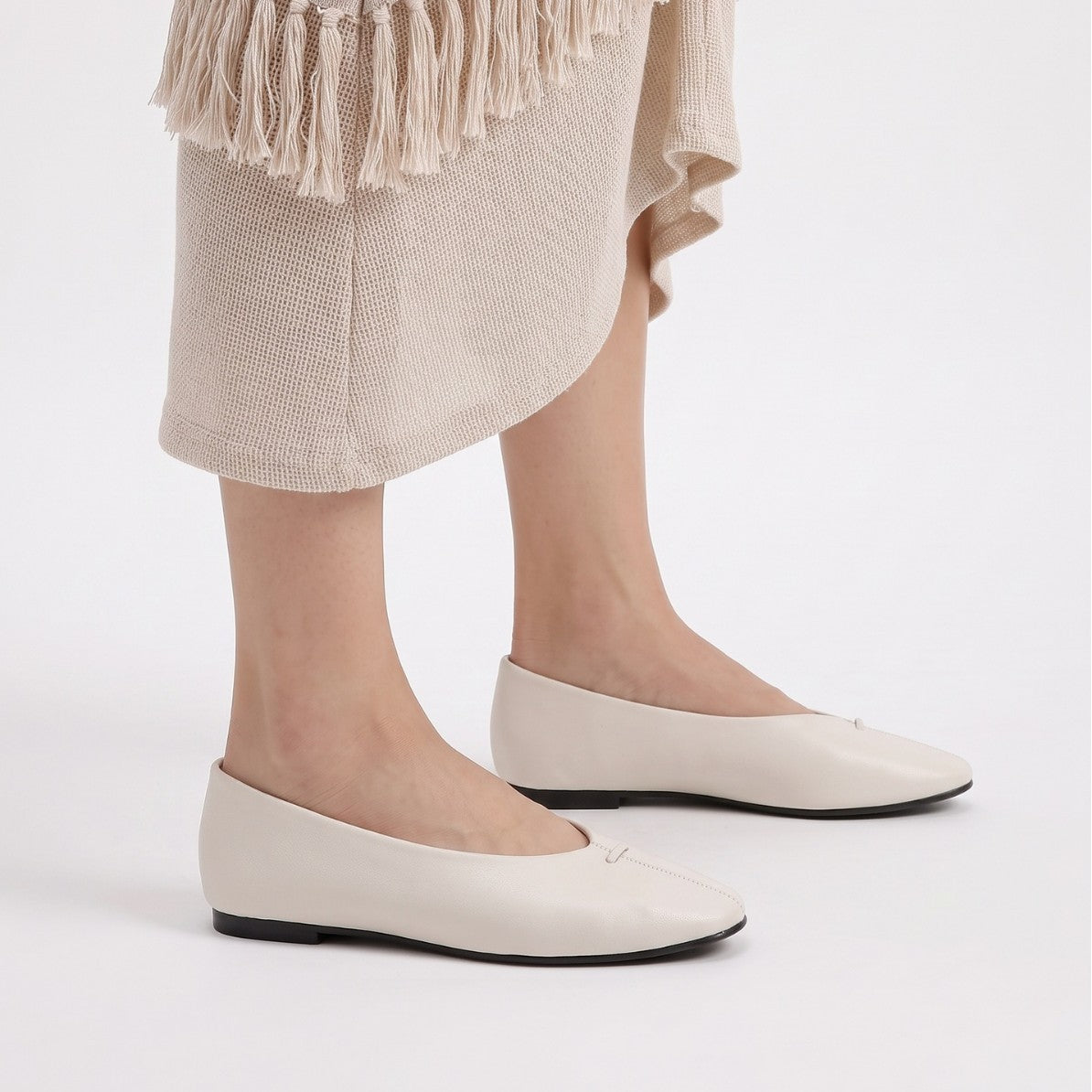 Mescini - off-white ballet flats worn standing under a knit skirt, US women's sizes