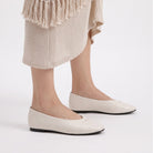 Mescini - off-white ballet flats worn standing under a knit skirt, US women's sizes