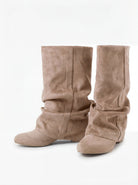 Mescini beige slouchy mid calf boots, worn by a model seated on a bench, US sizes