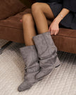 Mescini grey slouchy mid calf boots, worn by a model seated on a bench, US sizes