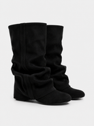 Mescini black slouchy mid calf boots, worn by a model seated on a bench, US sizes