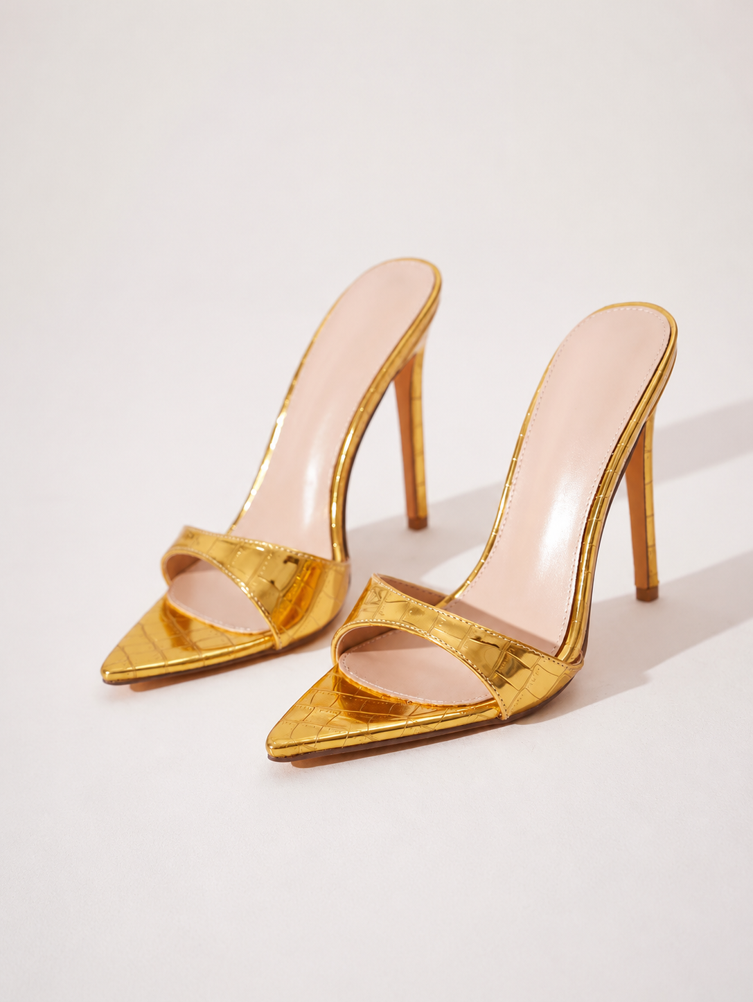 Mescini gold croc embossed pointed stiletto mules, the pair angled on a cream background, US women's sizes