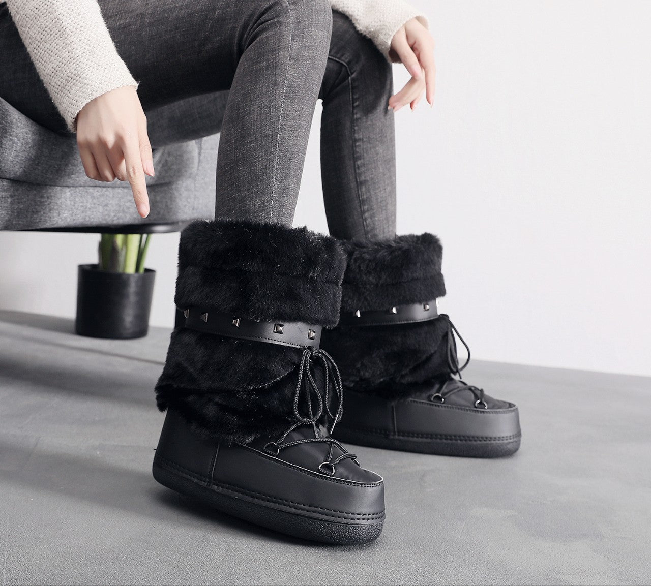 Mescini black faux fur studded platform snow boots, worn while seated on a chair, US women's sizes