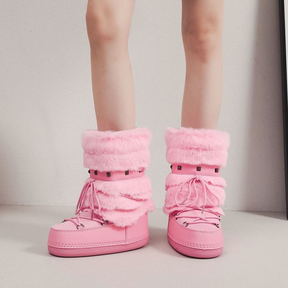 Mescini pink faux fur studded platform snow boots, worn by a model at a pale wall, US women's sizes