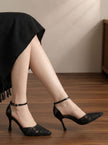 Mescini black floral mesh ankle strap pumps, worn by a model sitting on a wood floor, US women's sizes