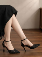 Mescini black floral mesh ankle strap pumps, worn by a model sitting on a wood floor, US women's sizes