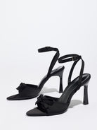 Mescini black satin bow ankle strap sandals, angled pair standing on a white surface, US women's sizes