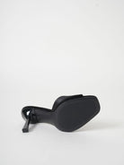 Mescini black wide band square toe mule on its side, the outsole facing out, US women's sizes