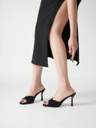 Mescini black wide band square toe mules worn standing with legs crossed, US women's sizes