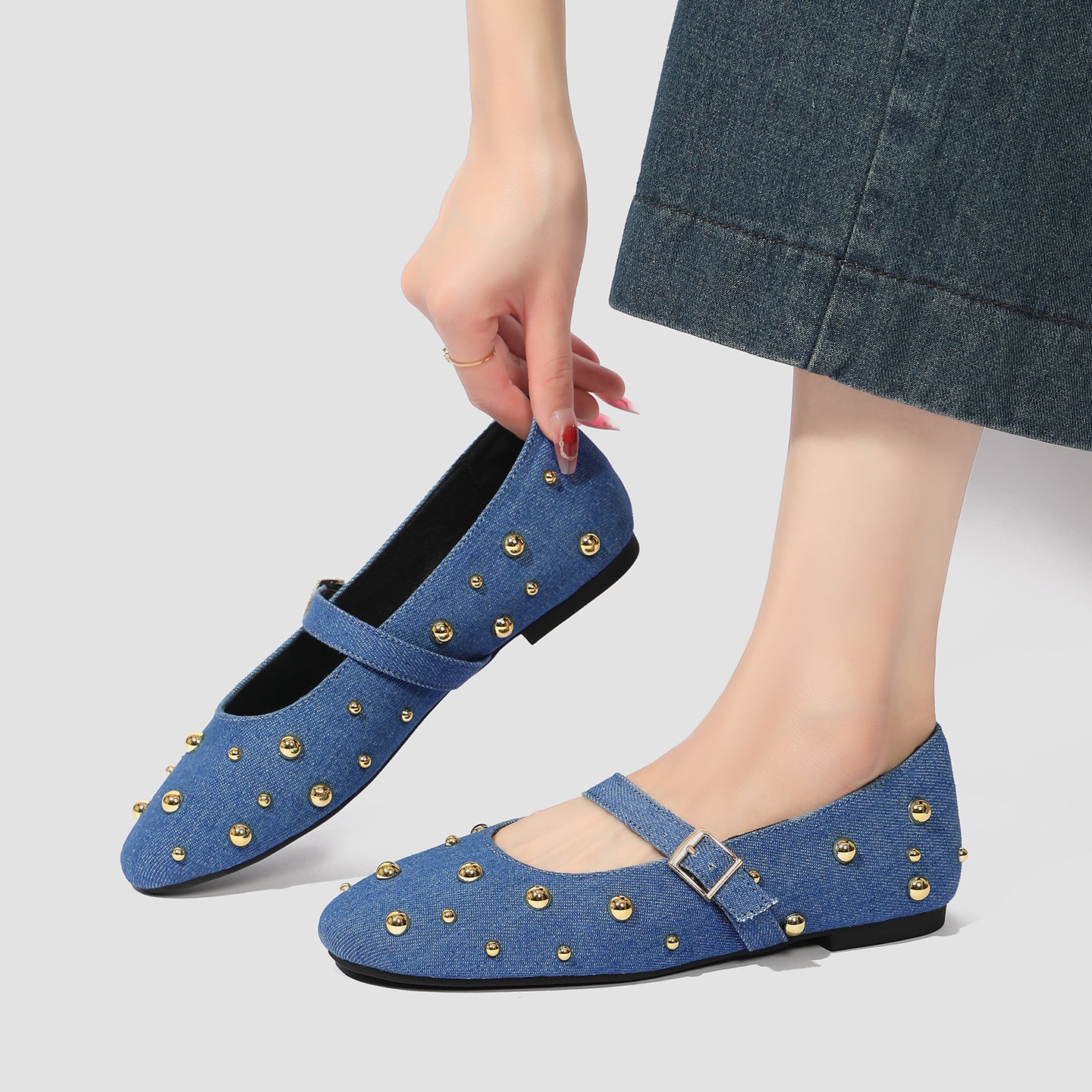 Mescini blue studded denim mary jane flats with a hand reaching down to them, US women's sizes
