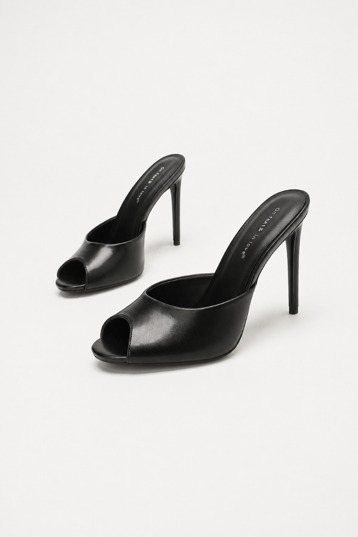 Mescini black sculpted peep toe stiletto mules, angled pair on a pale studio backdrop, US women's sizes