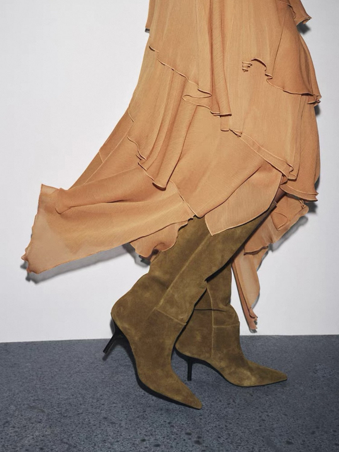 Mescini brown pointed toe wide shaft knee high boots worn under a ruffled dress, US women's sizes