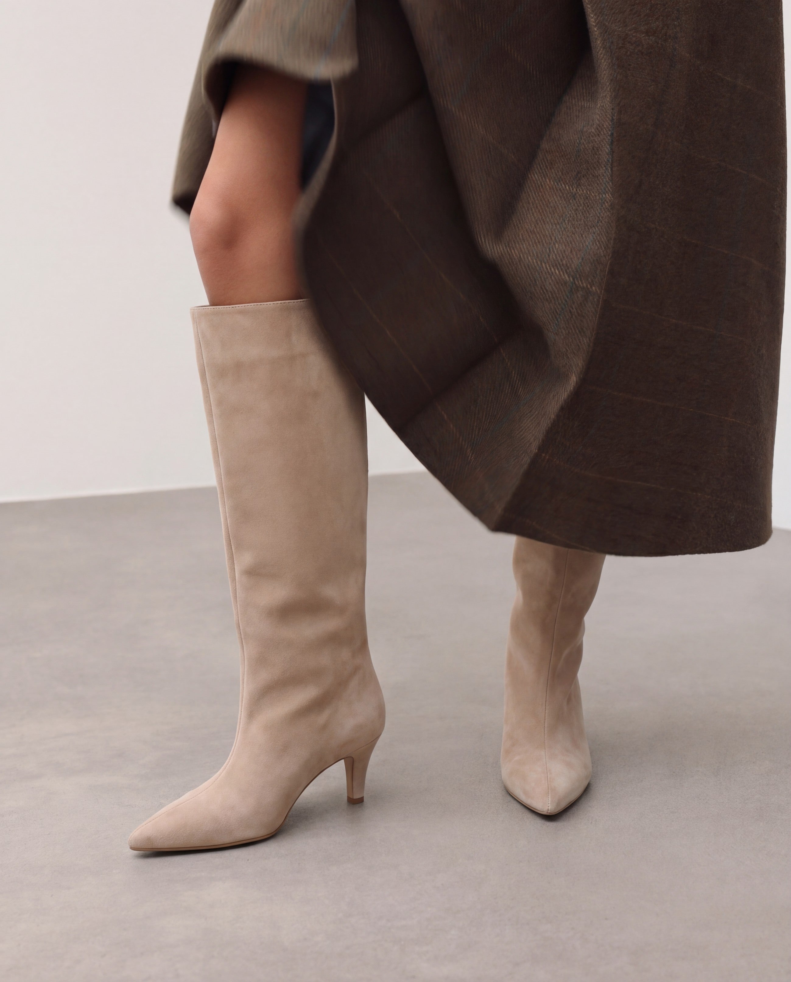 Mescini beige suede knee high boots, worn on the leg under a long coat, US sizes