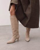 Mescini beige suede knee high boots, worn on the leg under a long coat, US sizes