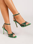 Mescini green rhinestone strappy stiletto sandals, worn on a model with one foot raised, US women's sizes