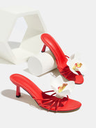 Mescini red orchid bloom strappy heeled mules, pair posed beside white blocks, US women's sizes
