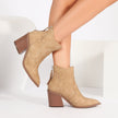 Mescini beige pointed toe western ankle boots, worn with one leg crossed over, US women's sizes