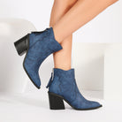 Mescini blue pointed toe western ankle boots, worn with the legs crossed over, US women's sizes