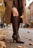 Mescini brown buckled pointed toe knee high boots, worn outdoors among fallen leaves, US women's sizes