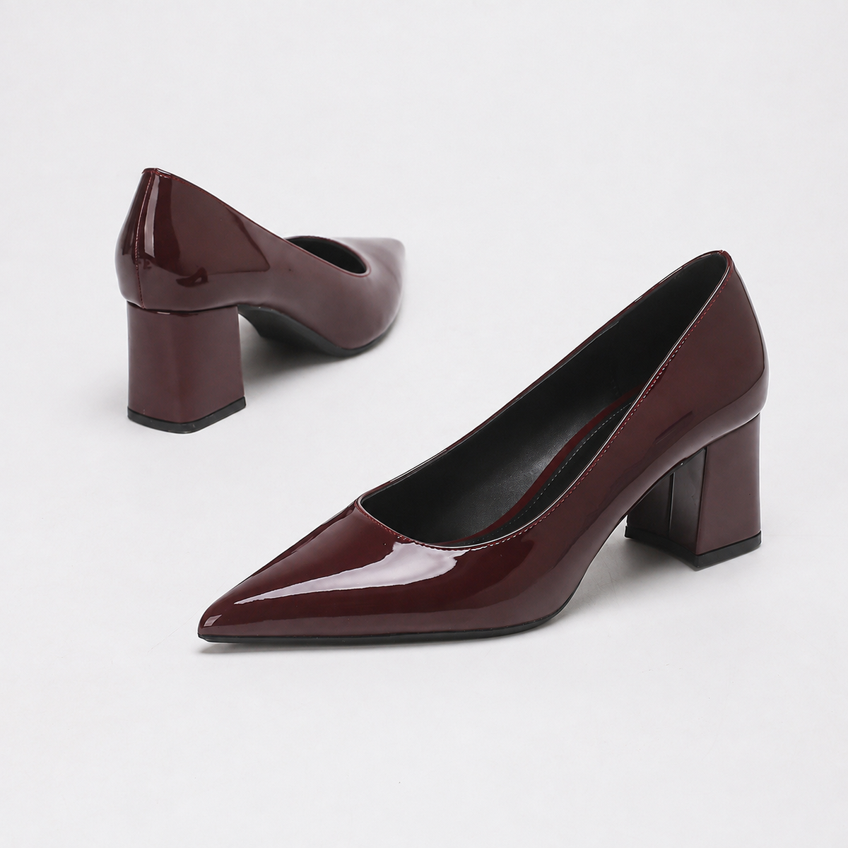 Mescini burgundy high shine pointed toe block heel pumps, pair angled with one shoe tipped, US women's sizes