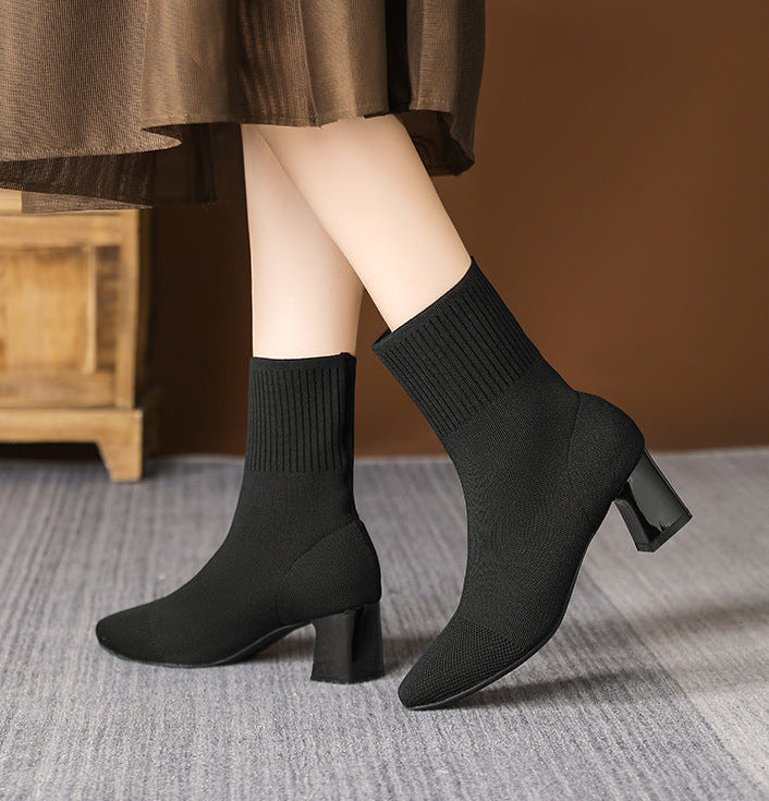 Mescini black knit square toe sock ankle boots, worn mid stride under a brown skirt, US women's sizes