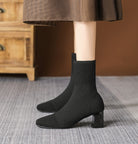 Mescini black knit square toe sock ankle boots, worn standing on a grey rug, US women's sizes
