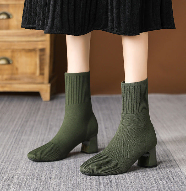 Mescini green knit square toe sock ankle boots, worn standing under a black skirt, US women's sizes