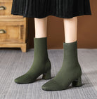 Mescini green knit square toe sock ankle boots, worn standing under a black skirt, US women's sizes