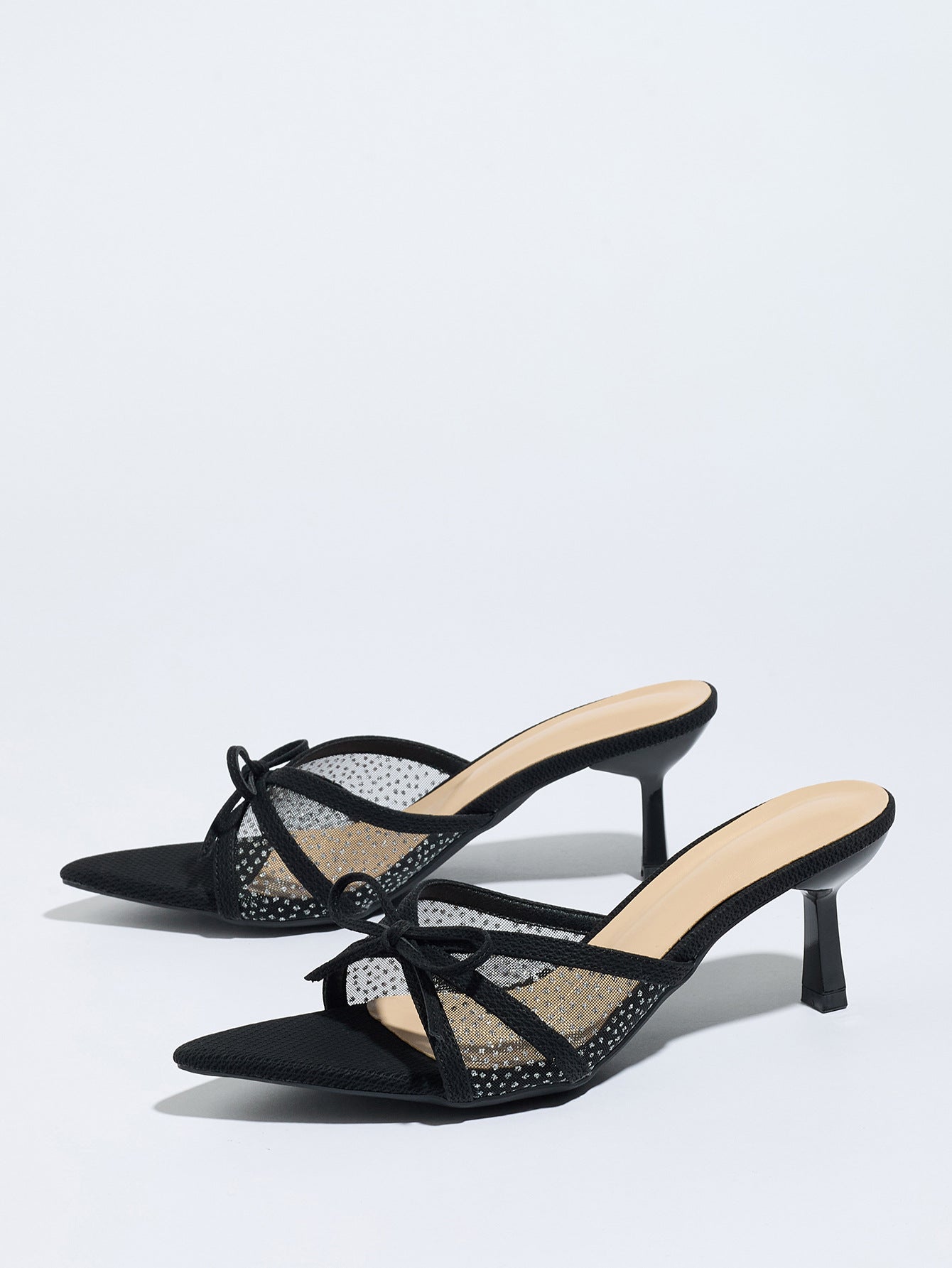 Mescini black bow mesh pointed toe mule heels, the pair angled on a white ground, US women's sizes