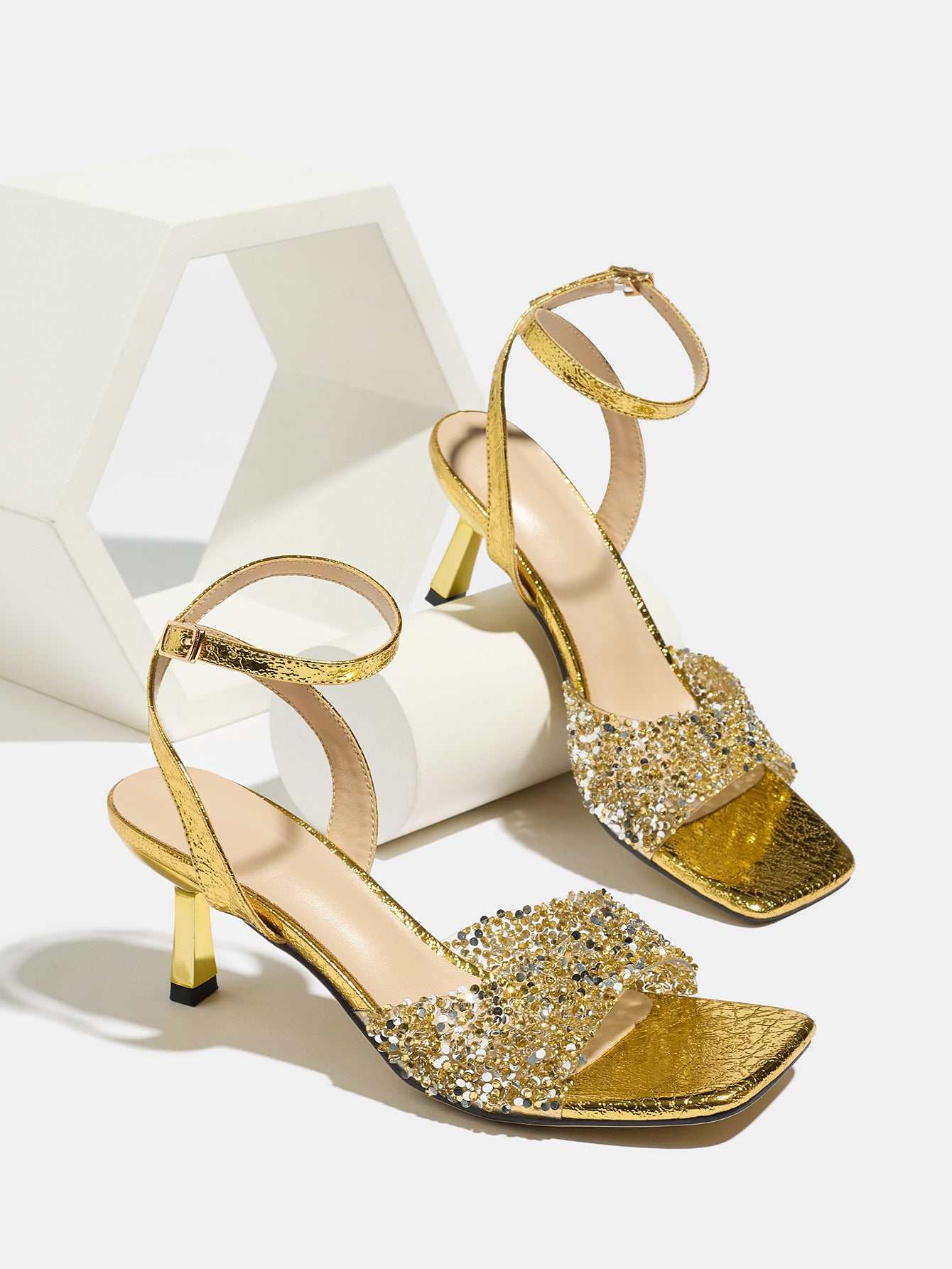 Mescini gold rhinestone square toe heeled sandals, pair styled on a white display prop, US women's sizes