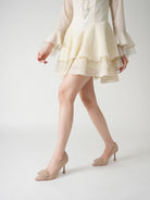 Mescini beige pointed toe stiletto pumps, worn by a model walking in a cream dress, US women's sizes