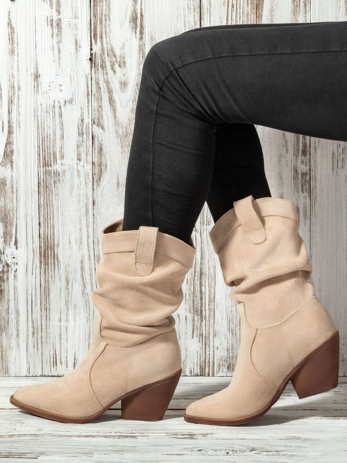 Mescini apricot slouch suede western cowboy boots, worn with black jeans by a wooden wall, US women's sizes