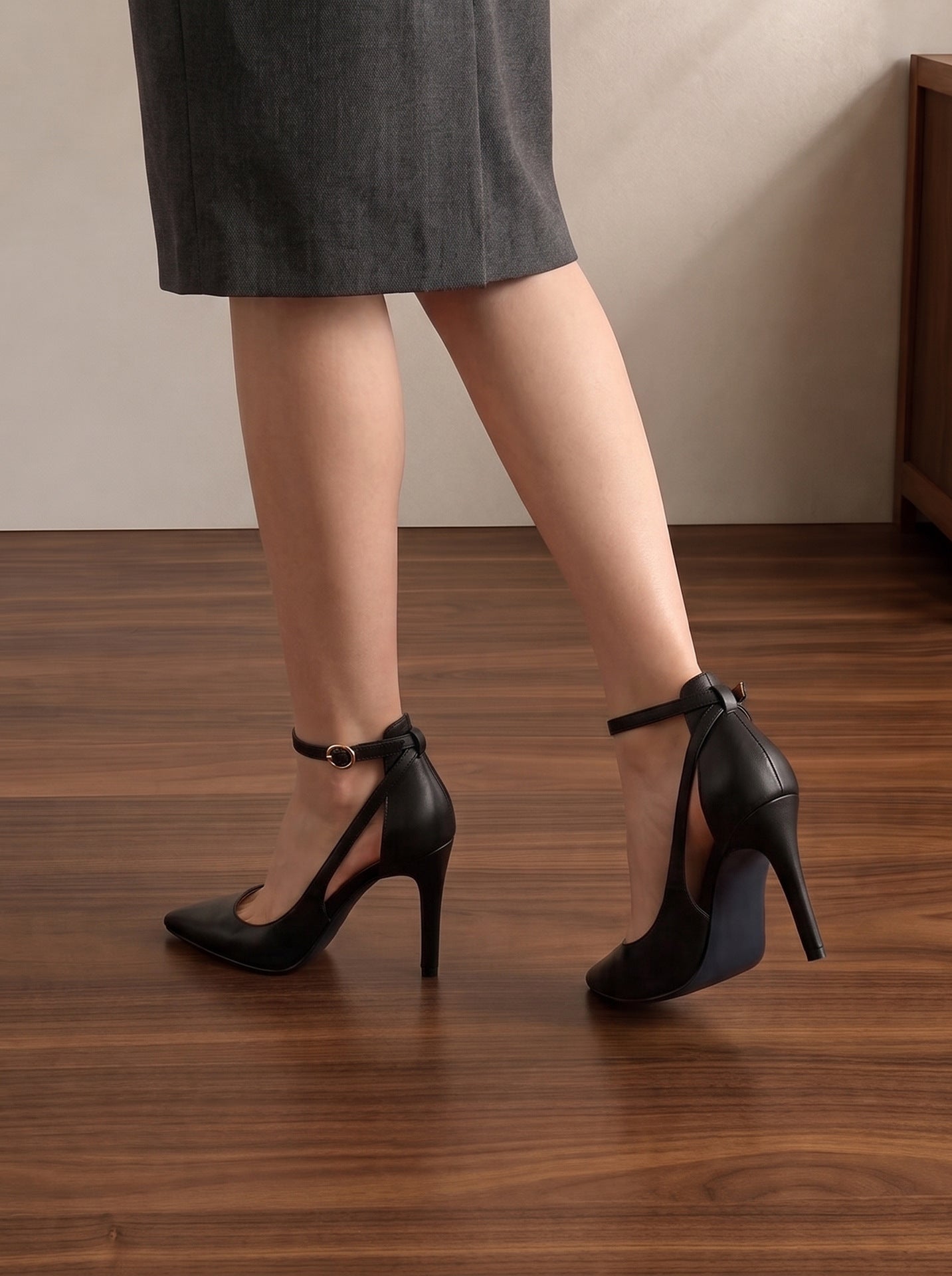 Mescini black pointed toe ankle strap stiletto pumps, worn mid stride from behind, US women's sizes