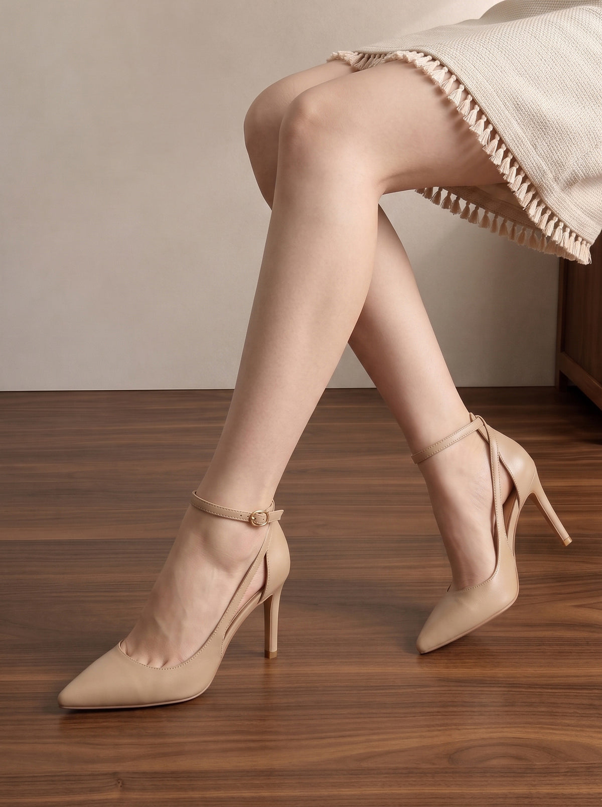 Mescini nude pointed toe ankle strap stiletto pumps, worn seated with a cream skirt, US women's sizes
