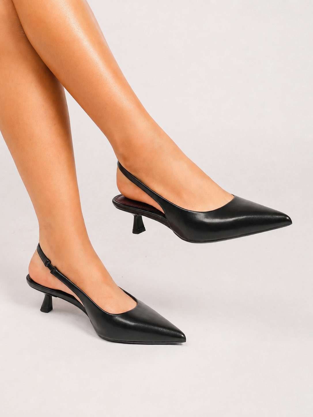 Mescini black pointed toe slingback kitten heels, worn by a model with legs crossed, US women's sizes