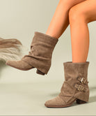 Mescini khaki ruched buckle mid calf slouch boots worn with one foot lifted, US women's sizes