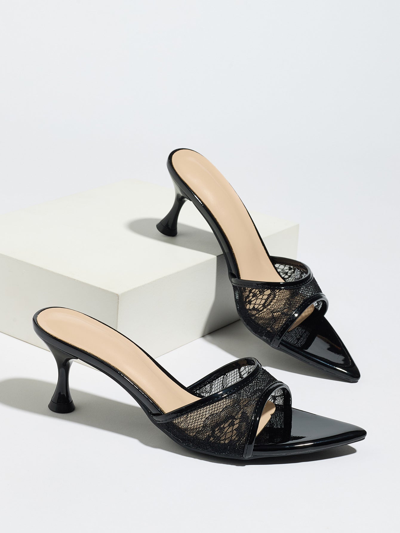 Mescini black sheer lace pointed toe mule heels, pair staged on white display blocks, US women's sizes