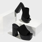 Mescini black knit platform mules staged on white blocks in a pair, US women's sizes