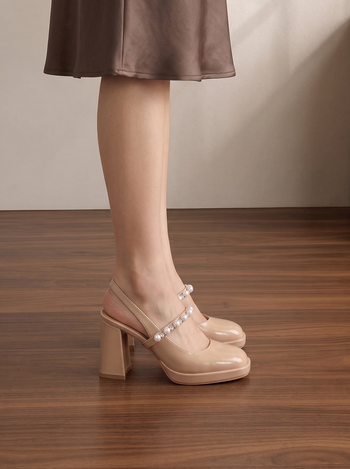 Mescini nude pearl strap platform mary jane heels, worn on a model standing on dark wood, US women's sizes